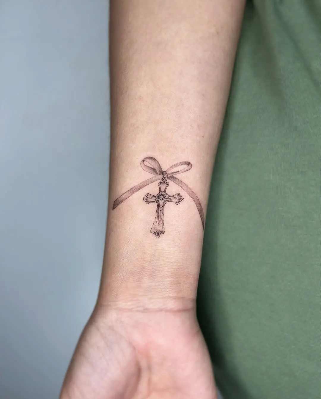 Elegant cross tattoo tied with a ribbon