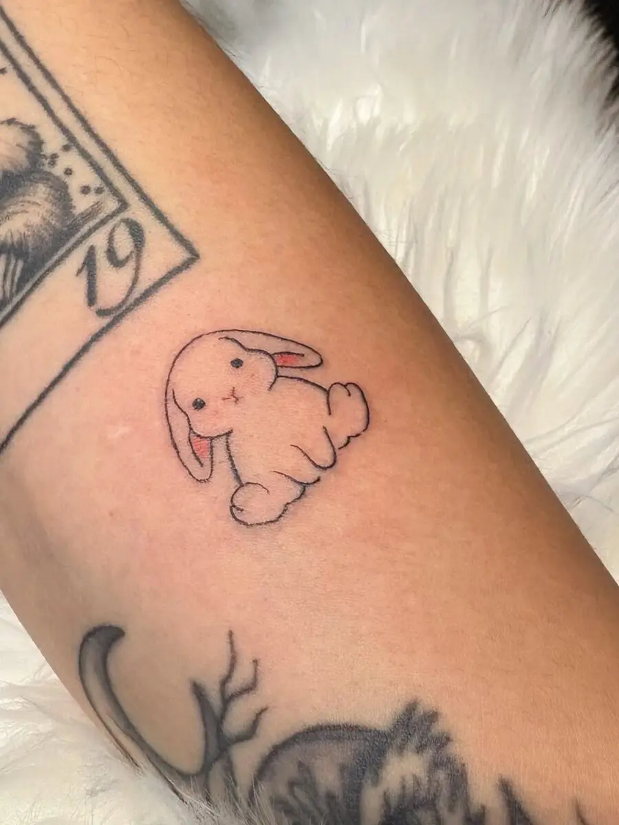 Adorable pink rabbit tattoo adorns the skin