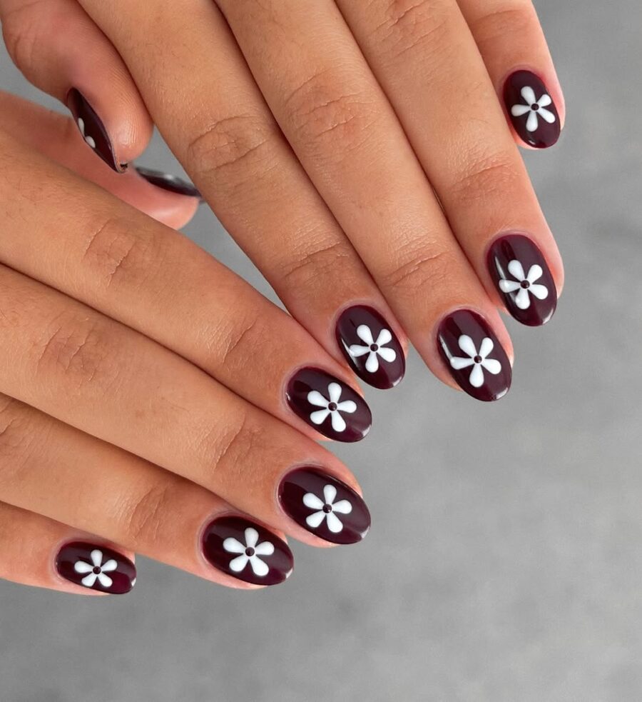 Chic burgundy nails with daisy accents