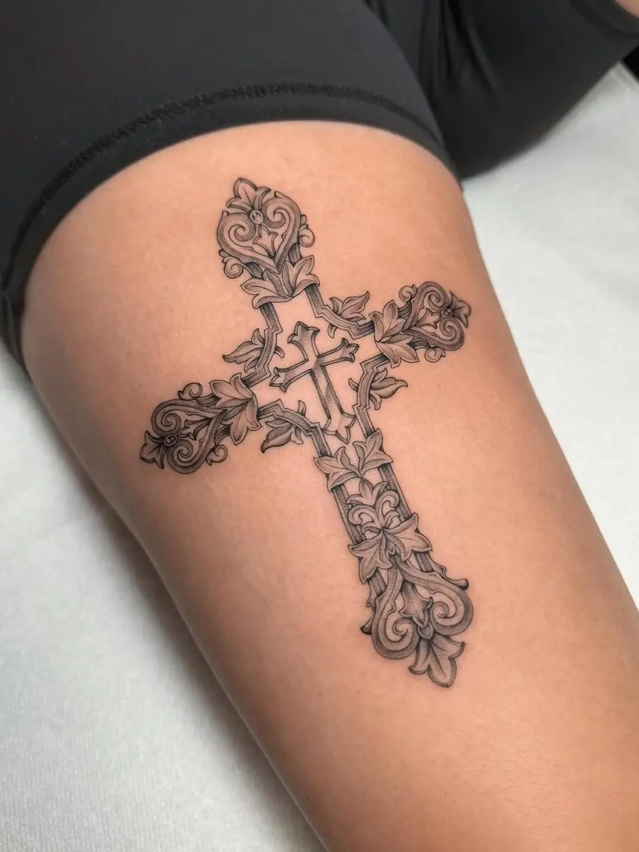 Intricate floral cross tattoo on thigh