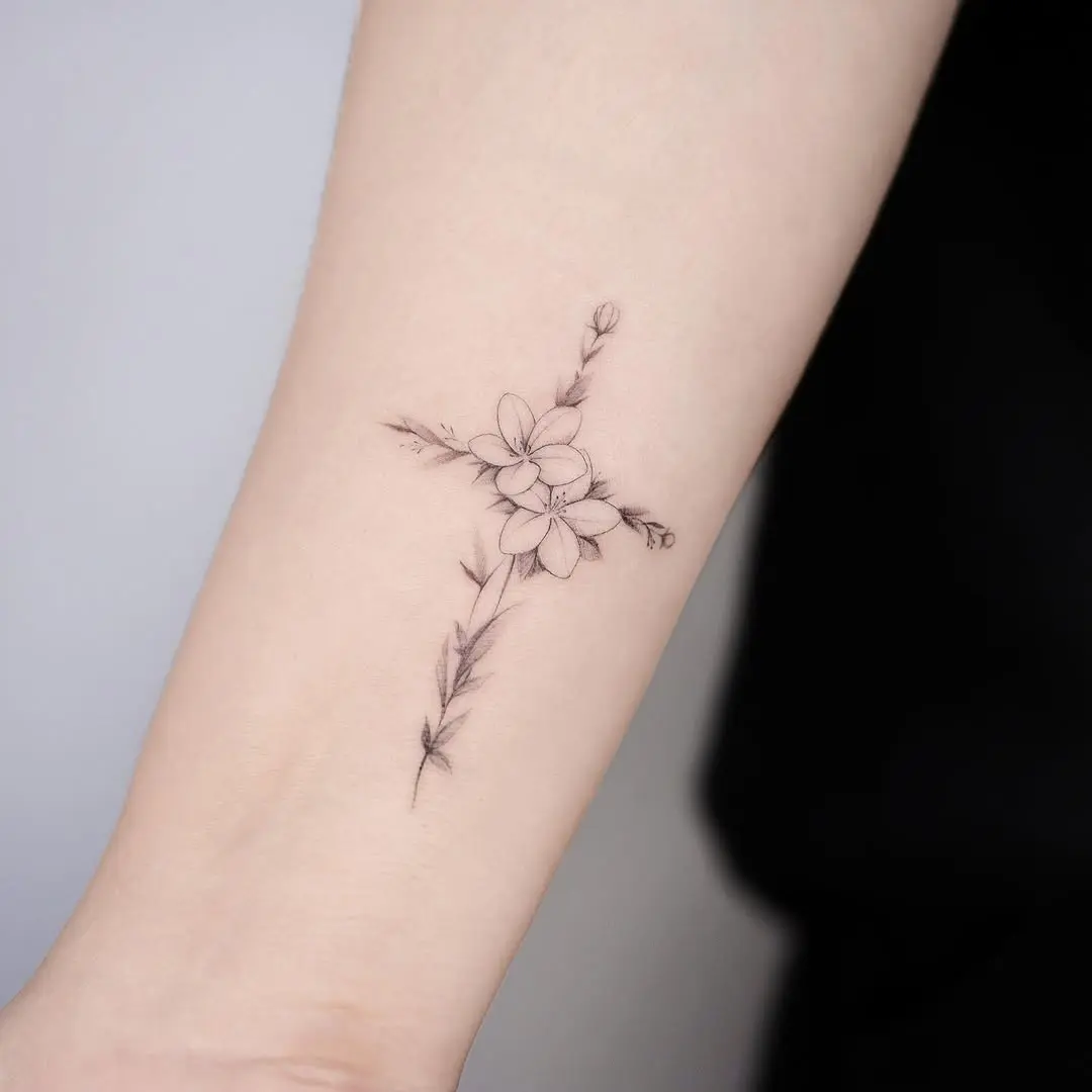 Delicate floral cross tattoo on the arm