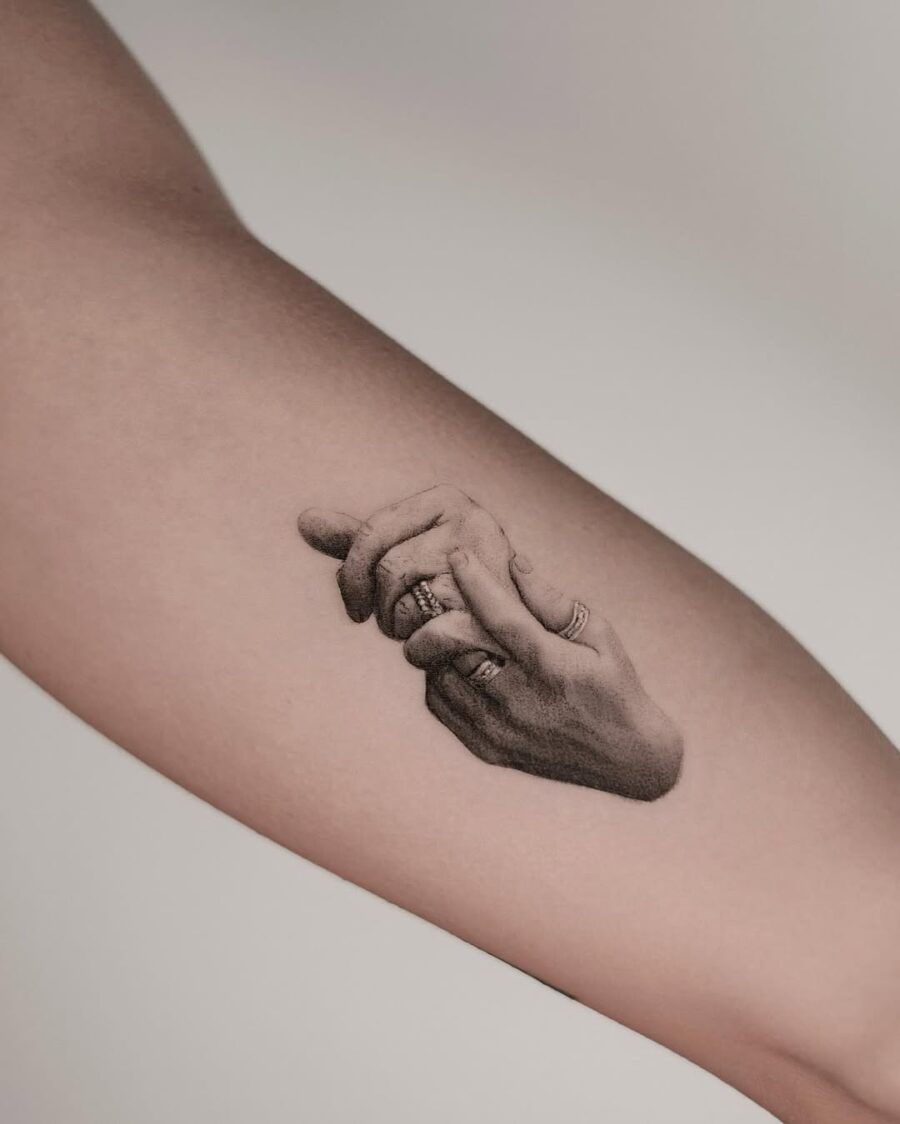Realistic tattoo of intertwined hands with rings