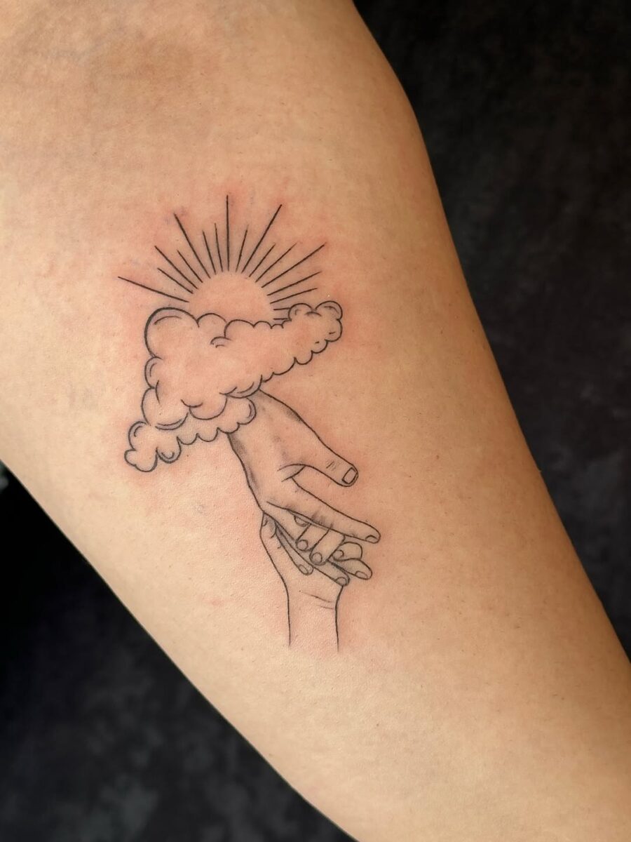 A unique tattoo of hands and clouds.