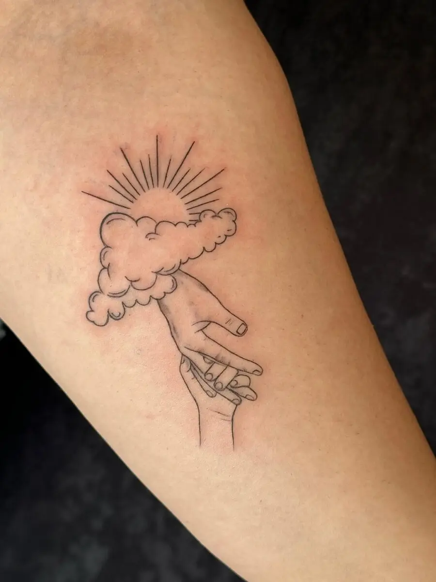 A unique tattoo of hands and clouds.