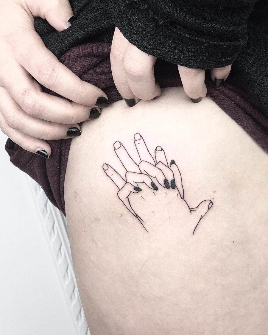 Delicate holding hands tattoo on thigh