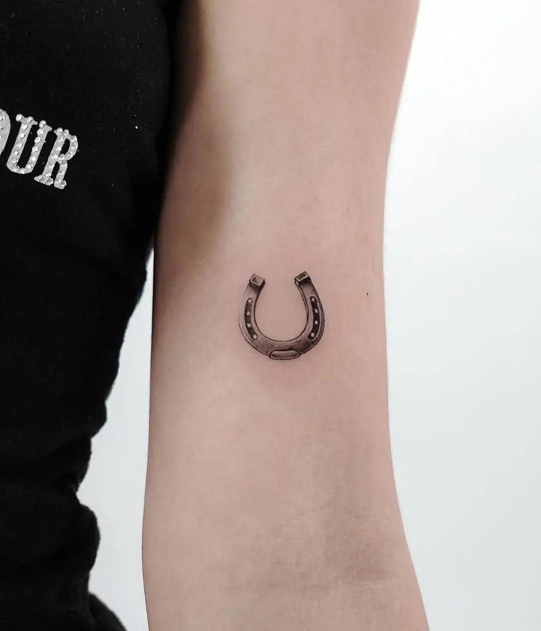Elegant minimal horseshoe tattoo on forearm