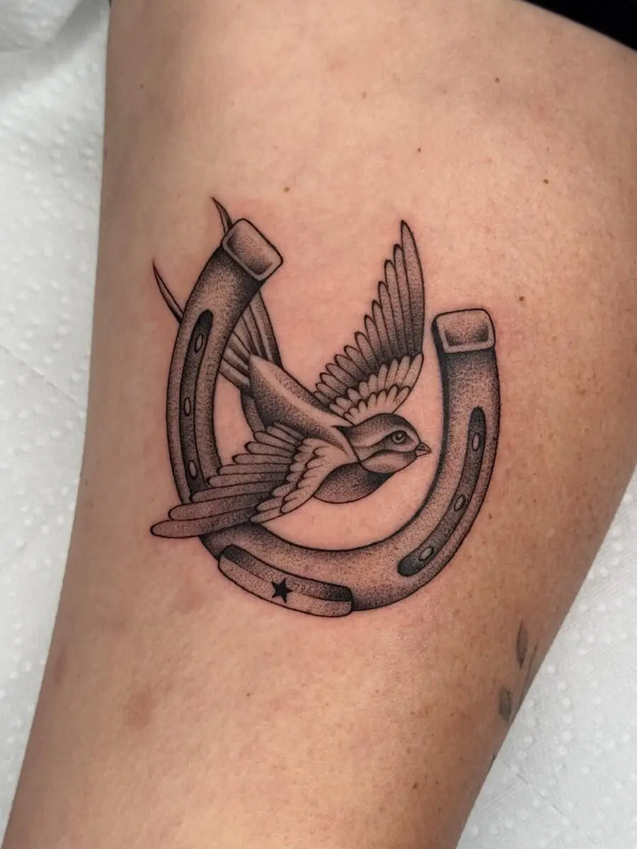 Elegant horseshoe tattoo featuring a flying bird