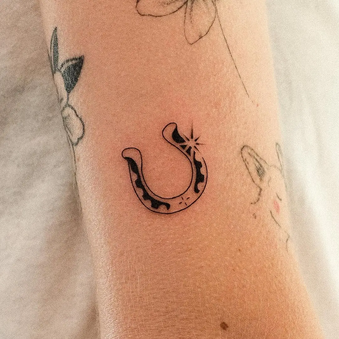 Minimalist horseshoe tattoo with floral elements