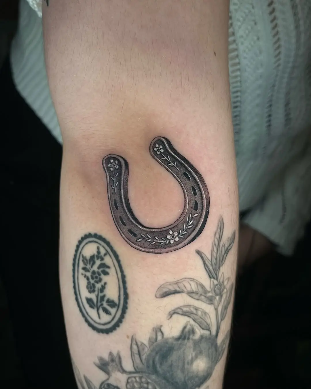Elegant horseshoe tattoo with floral accents