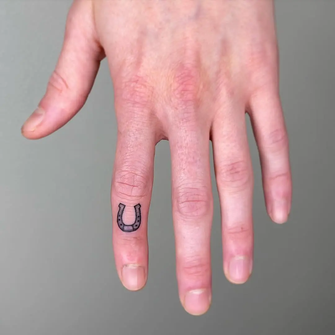 Minimalist horseshoe tattoo on a hand