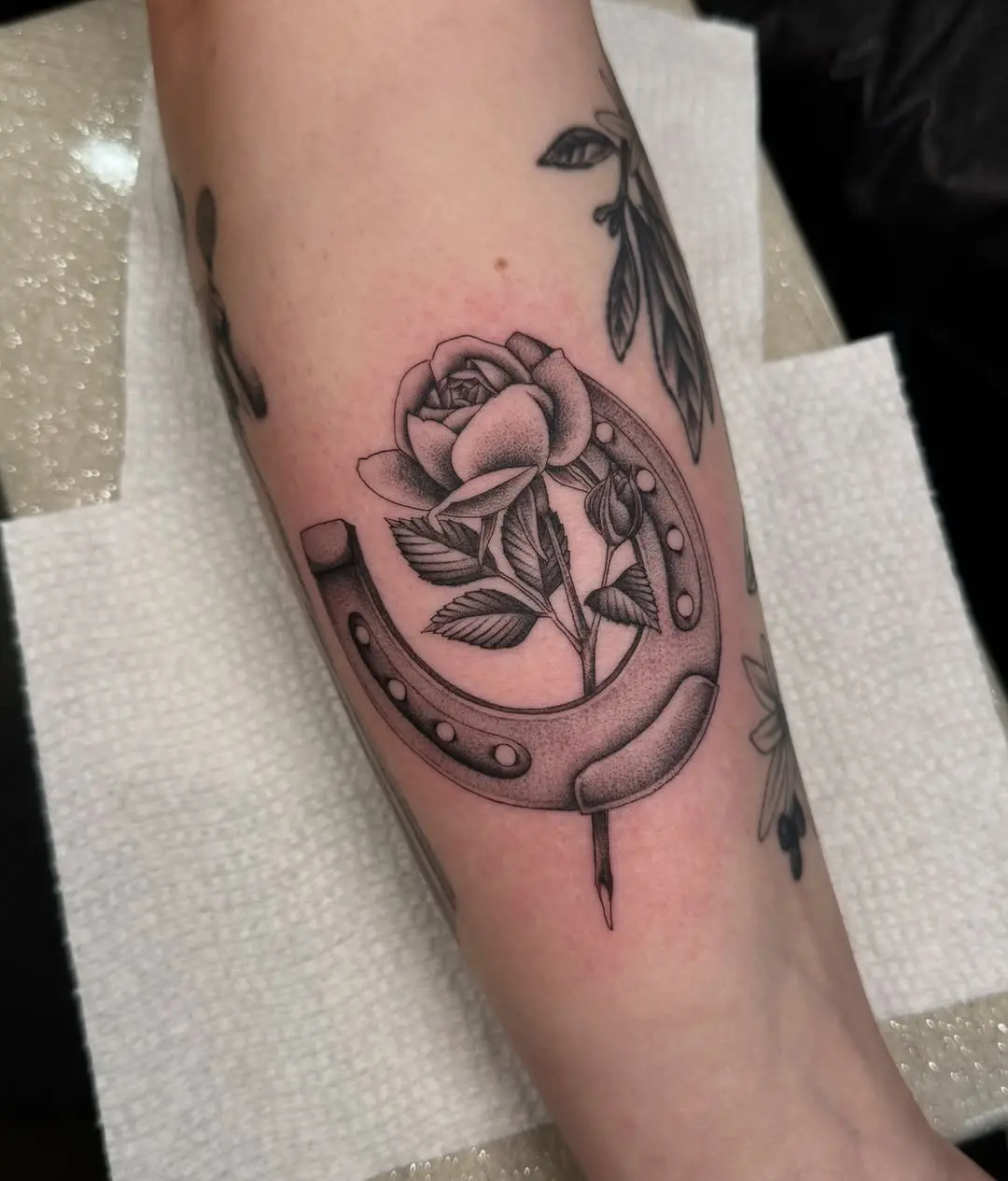Elegant horseshoe tattoo with floral accents