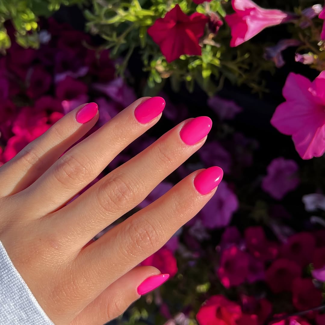 Vibrant hot pink nails in floral backdrop