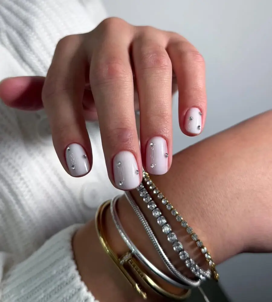 Elegant milky nails adorned with stud accents