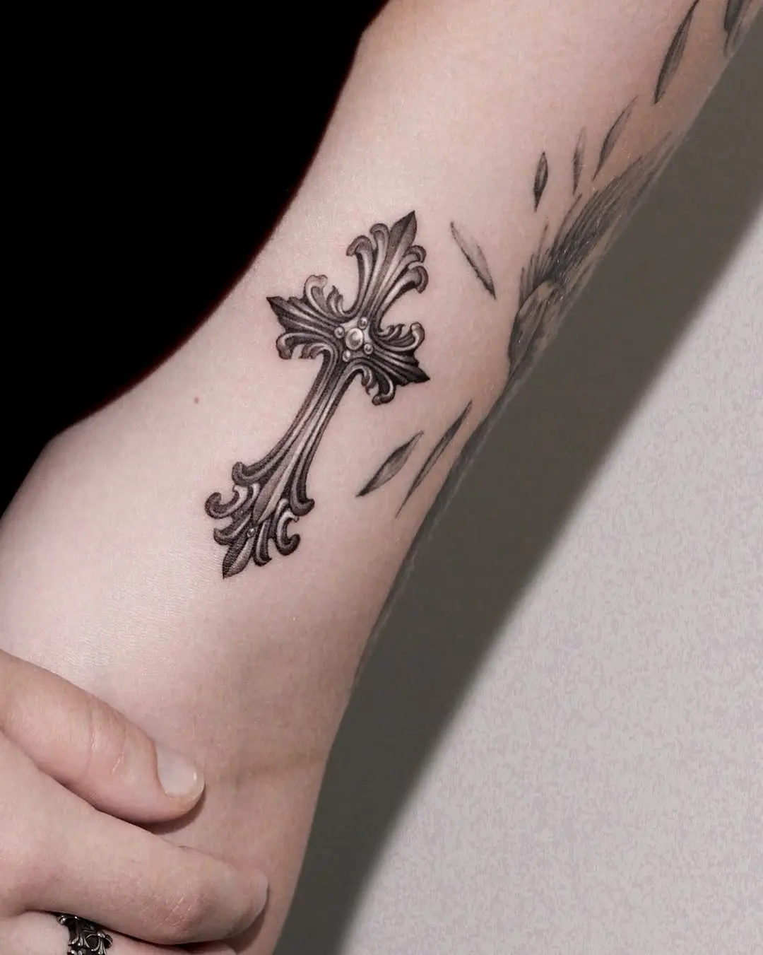 Elegant ornate cross tattoo in black ink