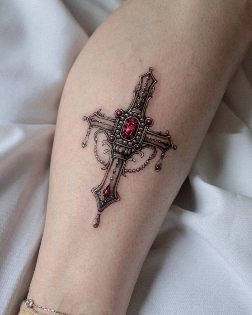Intricate cross tattoo with red gemstone details