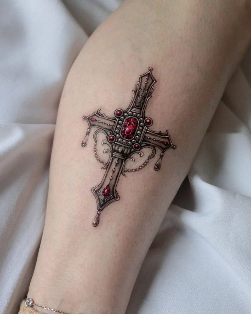 Intricate cross tattoo with red gemstone details
