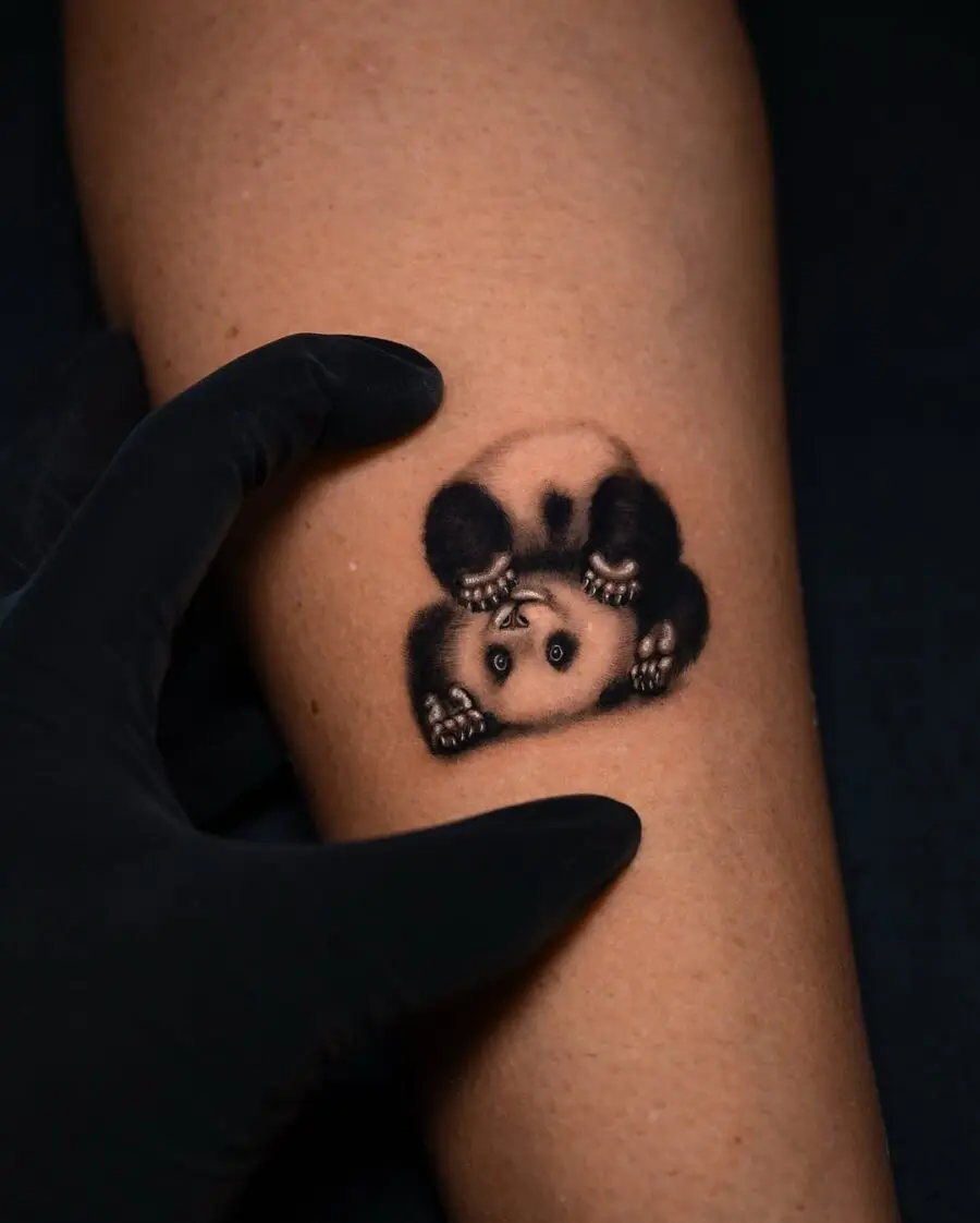 Realistic panda tattoo with playful pose