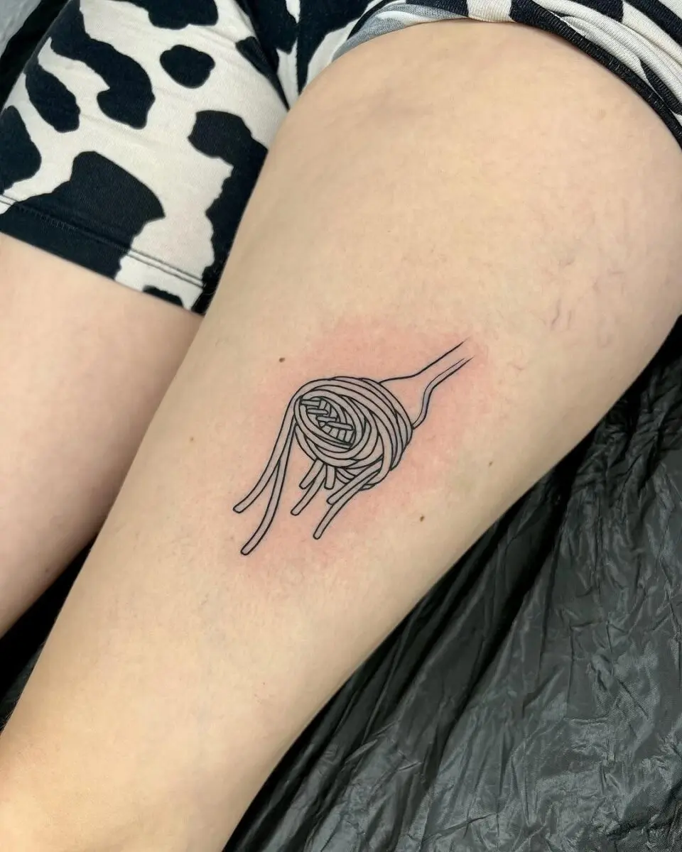 Charming pasta tattoo on a thigh.