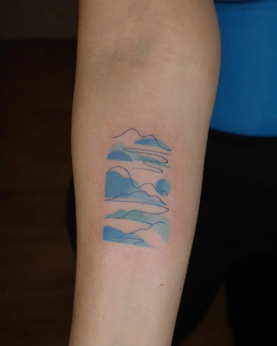 Serene mountains tattoo with calming blue hues
