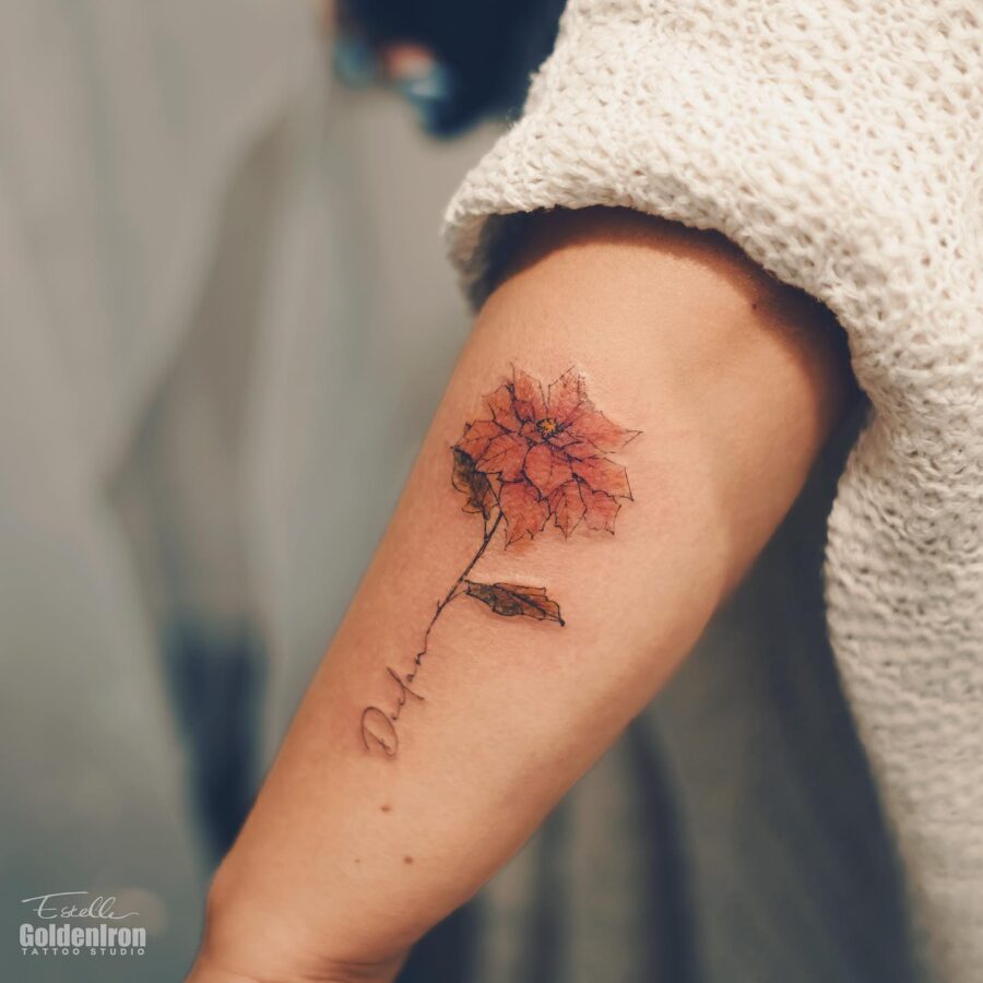 Delicate poinsettia tattoo on an elegant arm