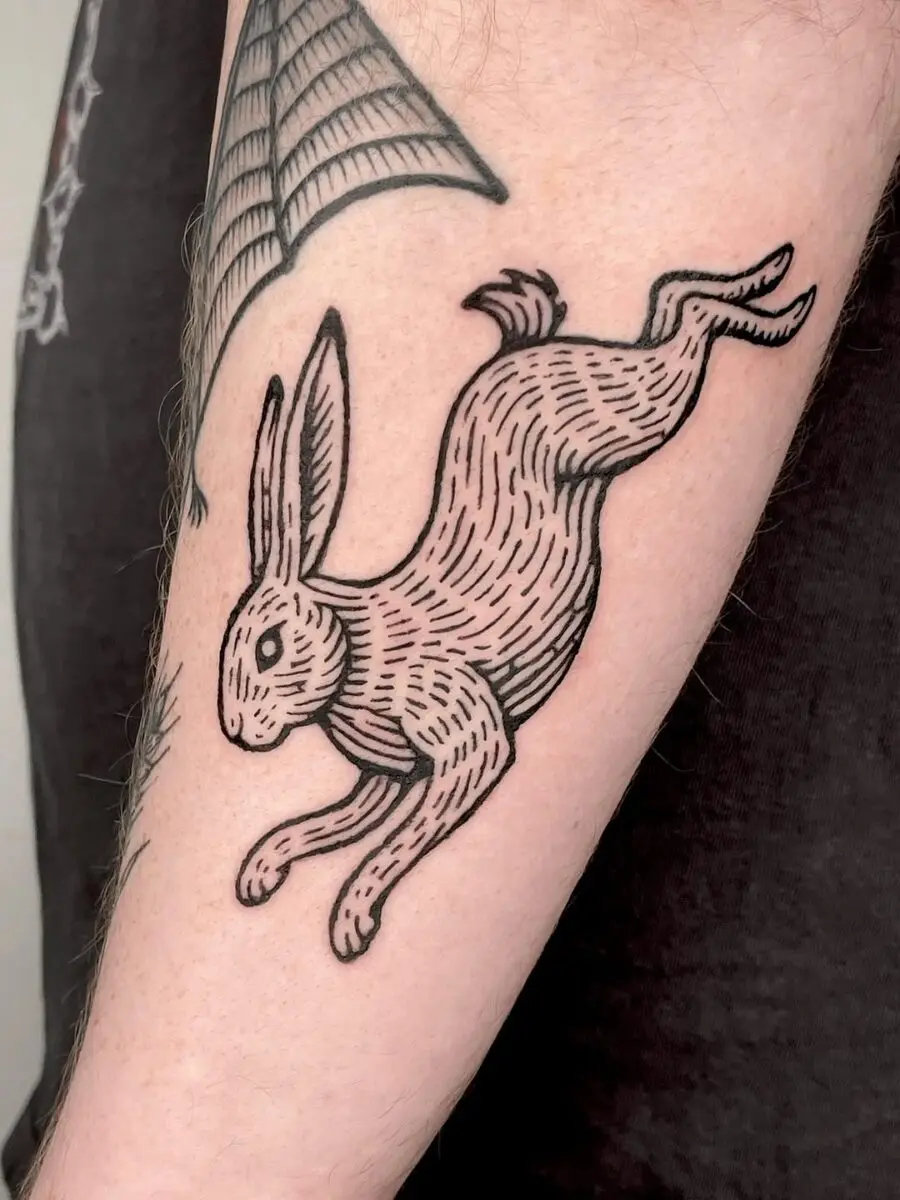 Playful leaping rabbit tattoo in black ink