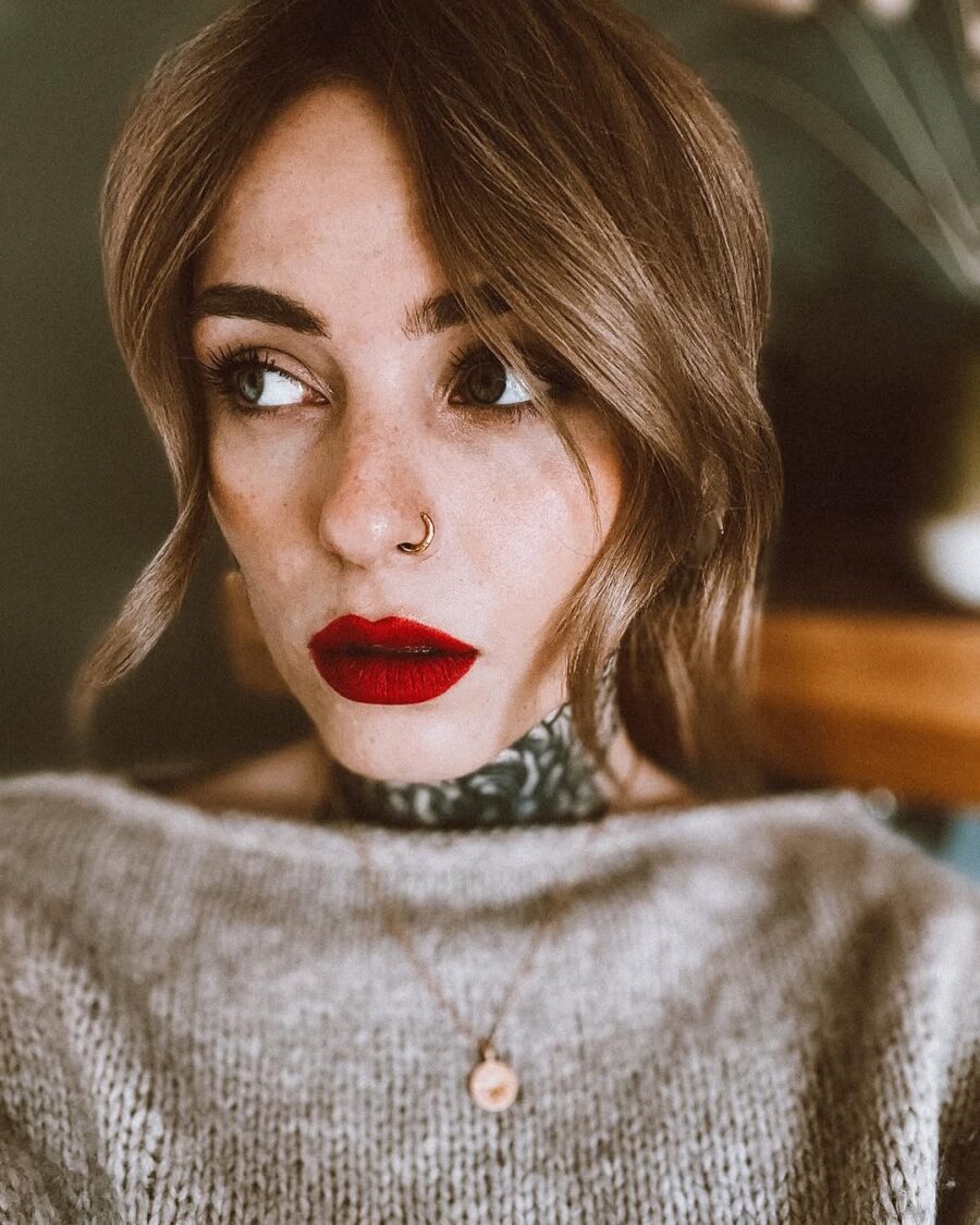 Bold red lip complements subtle makeup vibes.