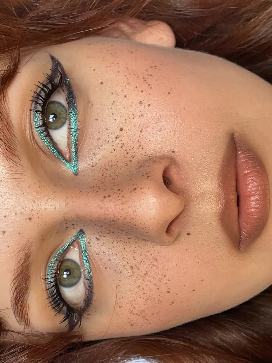 Vibrant teal eyeliner with natural freckles