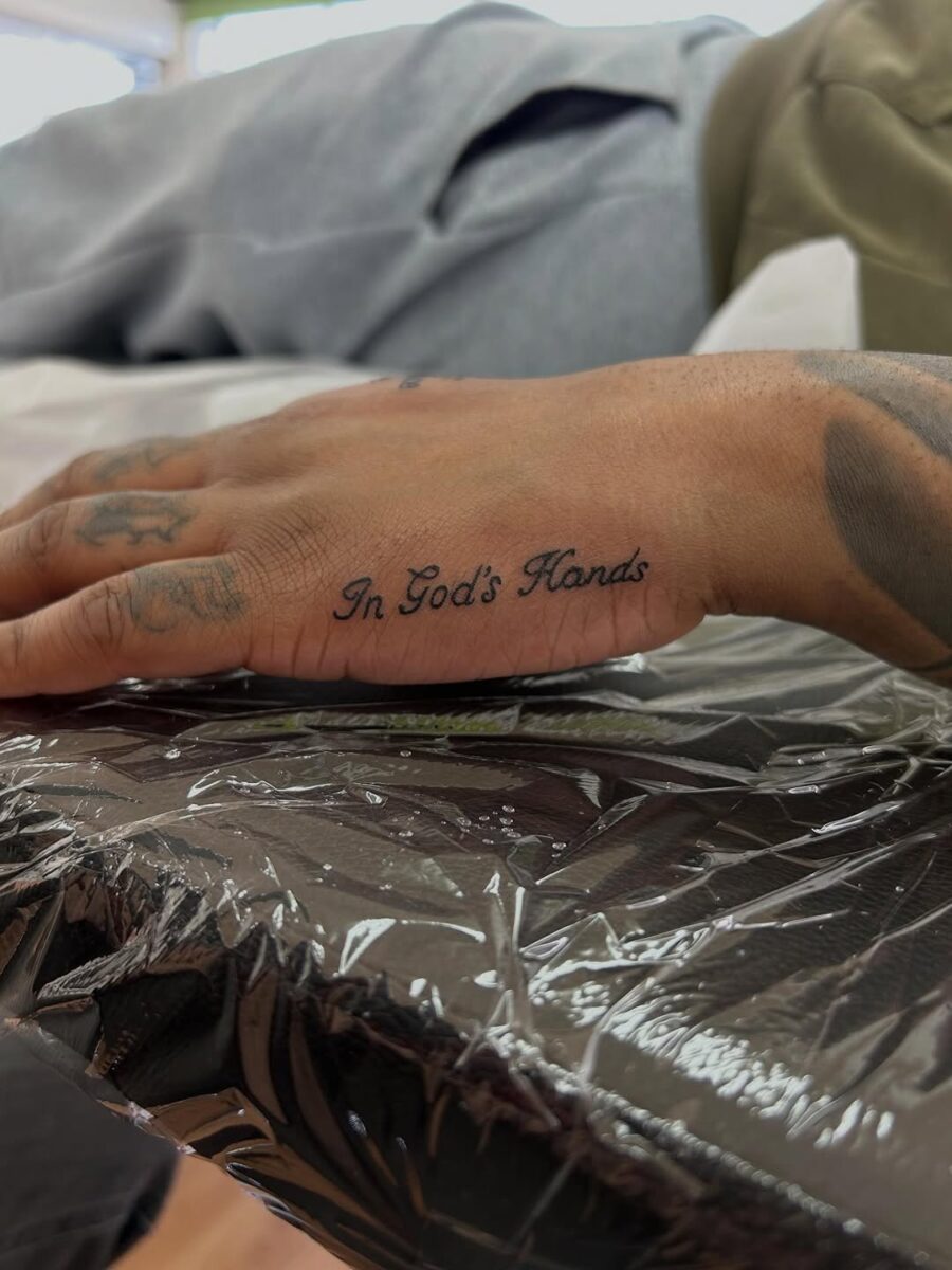 Elegant script tattoo on hand exudes spirituality