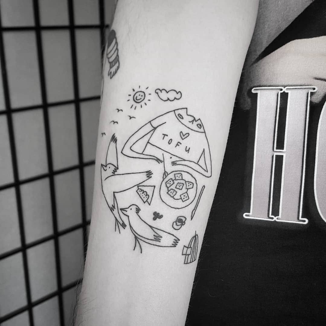 Playful vegan-themed tattoo with birds and tofu