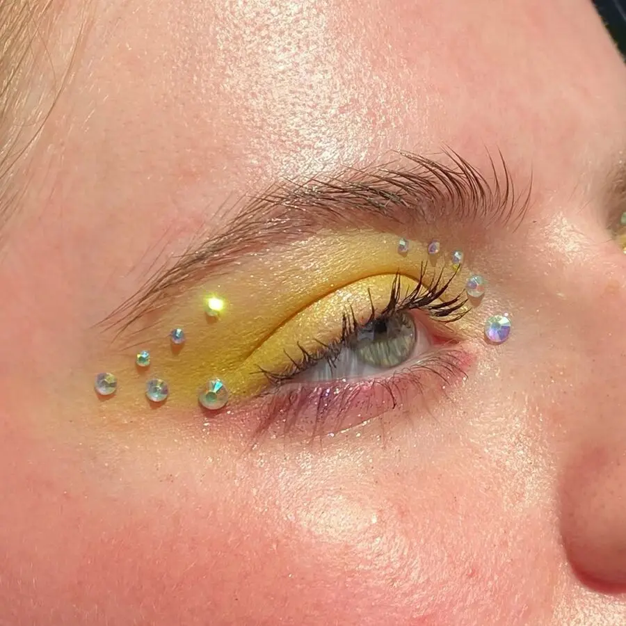 Vibrant yellow eye makeup with gem accents