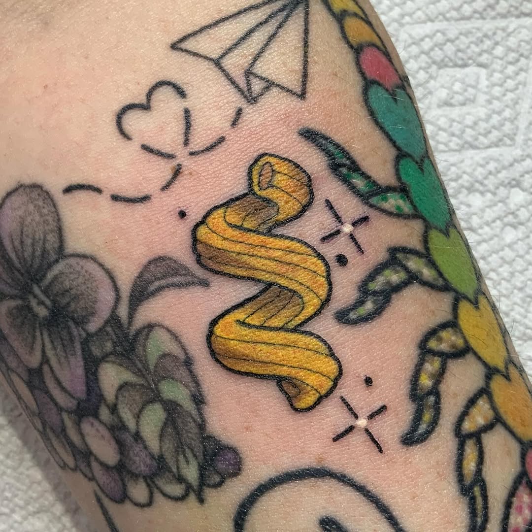 Whimsical yellow pasta design on forearm