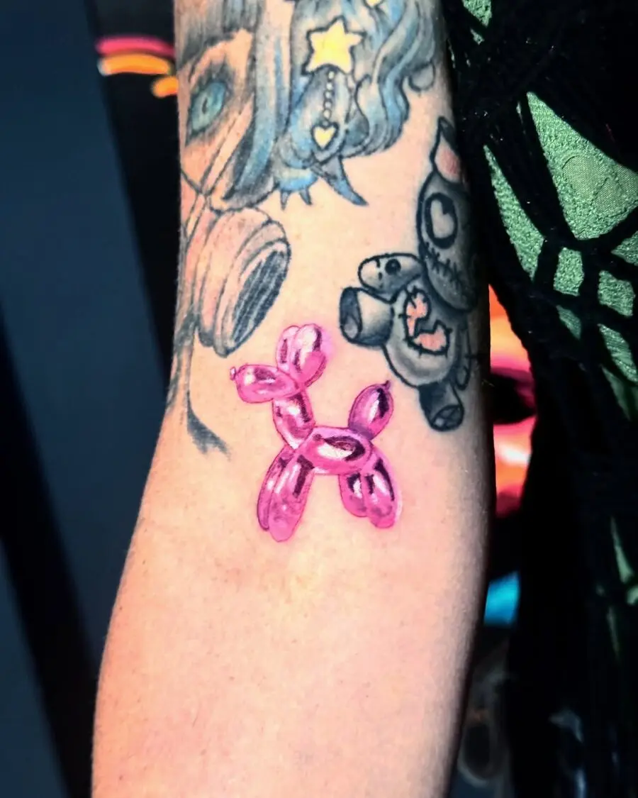 A vibrant pink balloon dog tattoo on arm