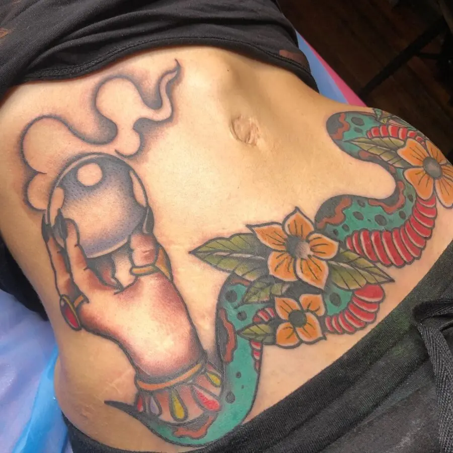 Colorful belly tattoo showcasing hand and snake