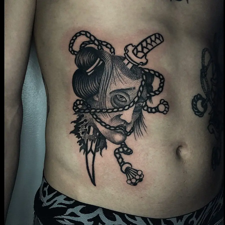 Intricate belly tattoo featuring a woman and blades.