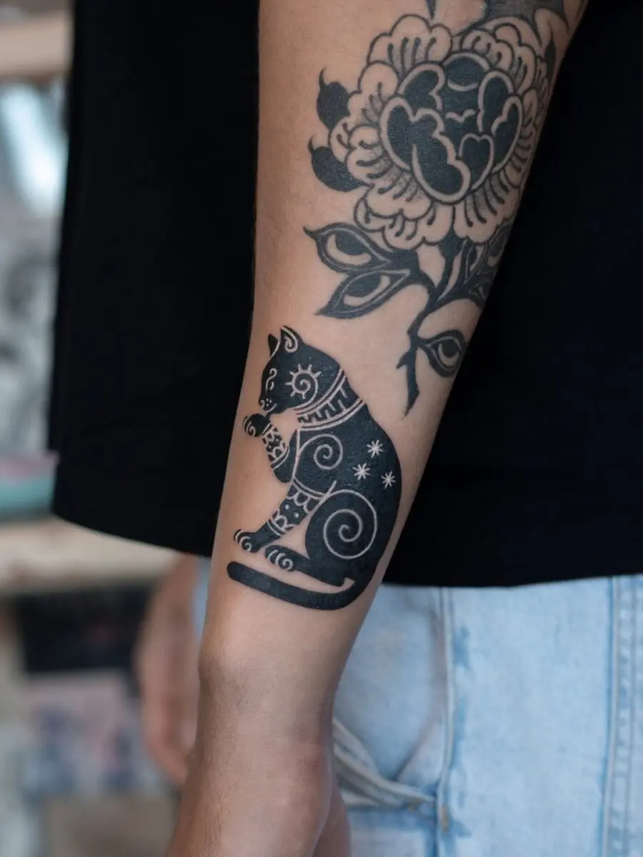Intricate black cat tattoo with swirling patterns