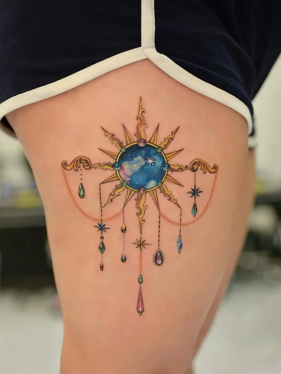Glamorous celestial sun tattoo with hanging gems