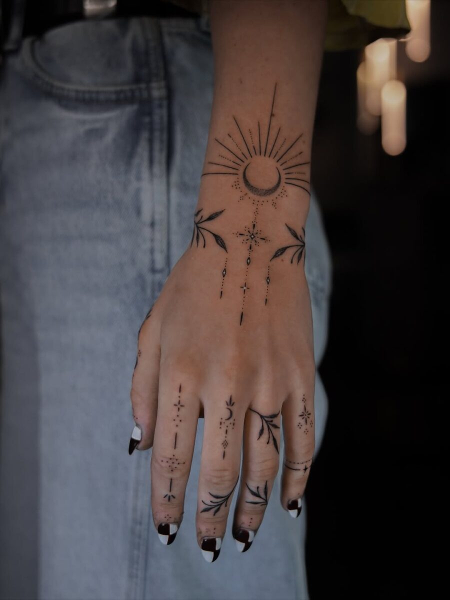 Artistic celestial tattoos adorn the hand beautifully