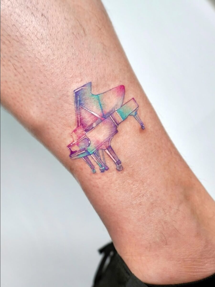 Vibrant grand piano tattoo on the leg
