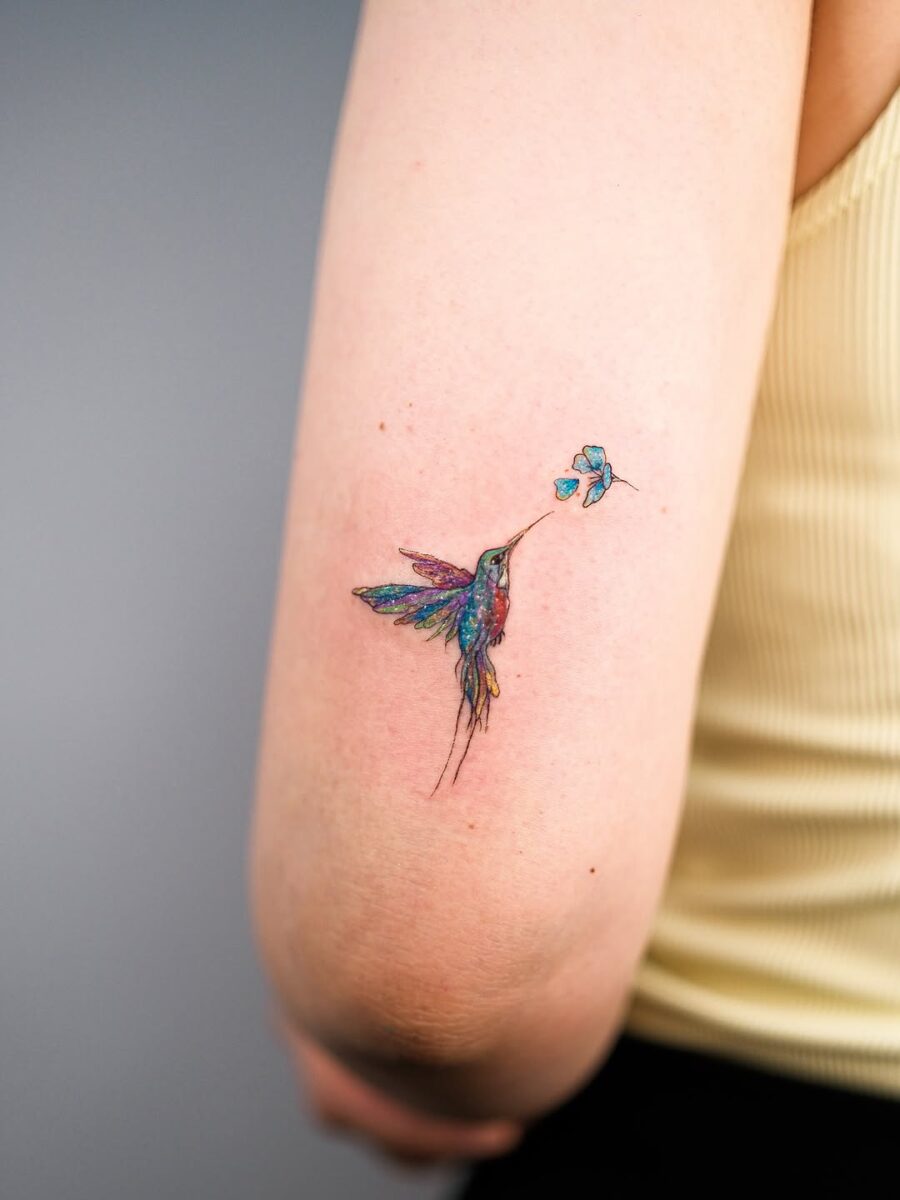 Vibrant hummingbird tattoo sipping from flower