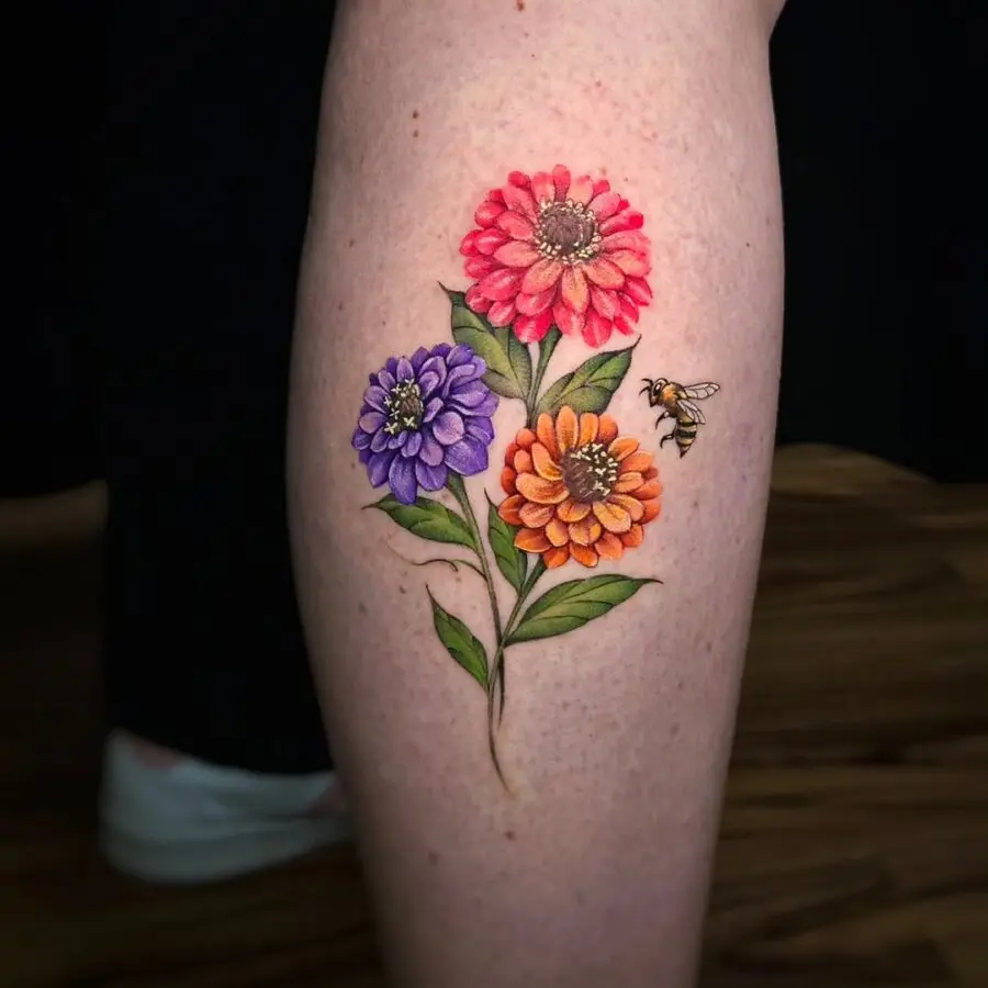 Vibrant zinnia tattoo with a charming bee