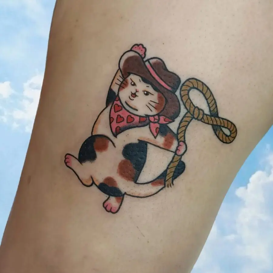 Playful cowboy cat tattoo with charm
