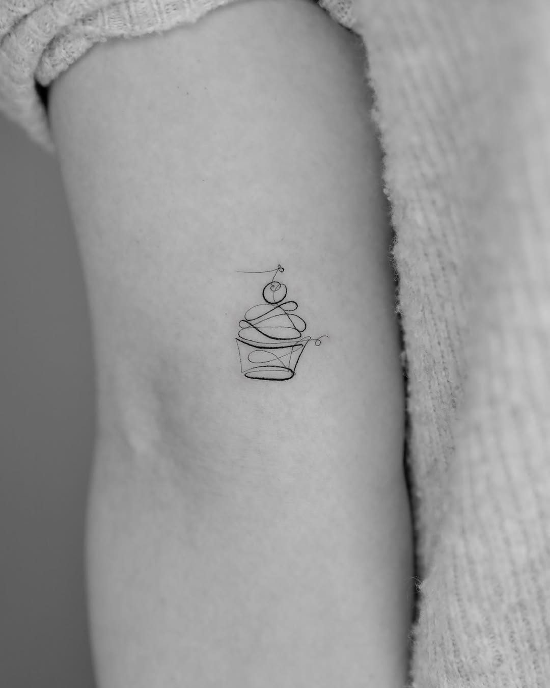 Delicate black line art cupcake tattoo design