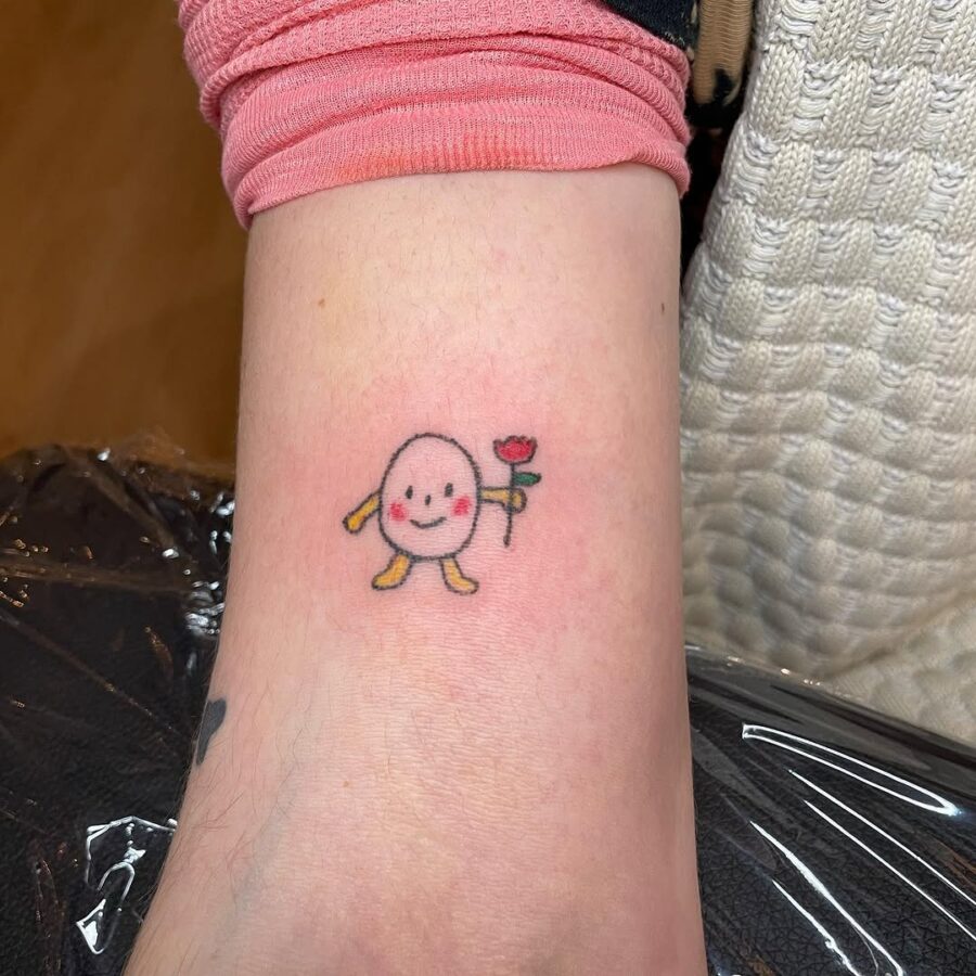 Charming egg character holding a flower tattoo