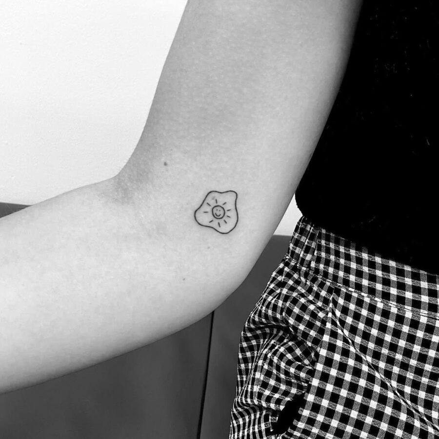Charming fried egg tattoo with a smiling face