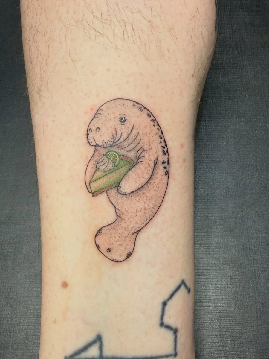 Adorable manatee tattoo with a slice of cake