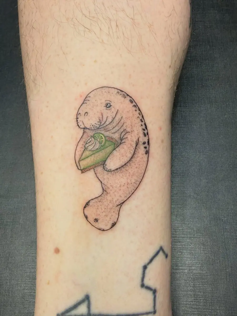 Adorable manatee tattoo with a slice of cake