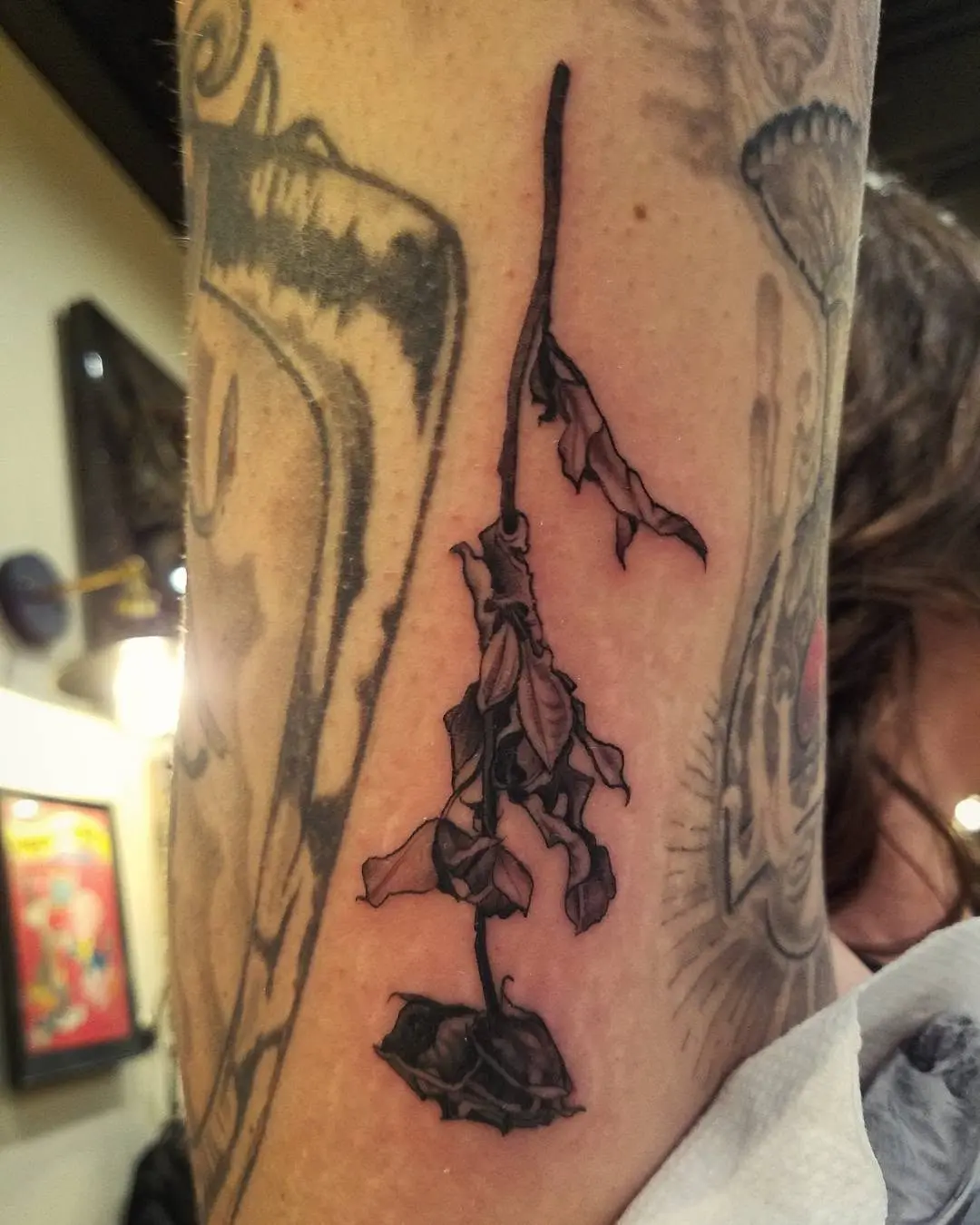 Expressive black dead flower tattoo on arm