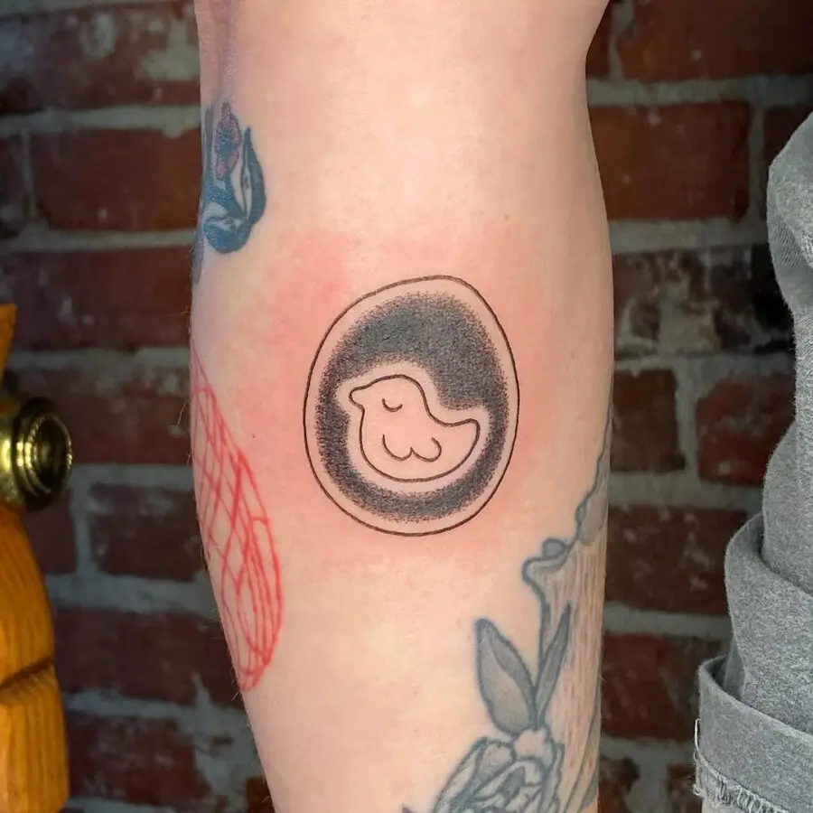 Playful bird in an egg-inspired tattoo
