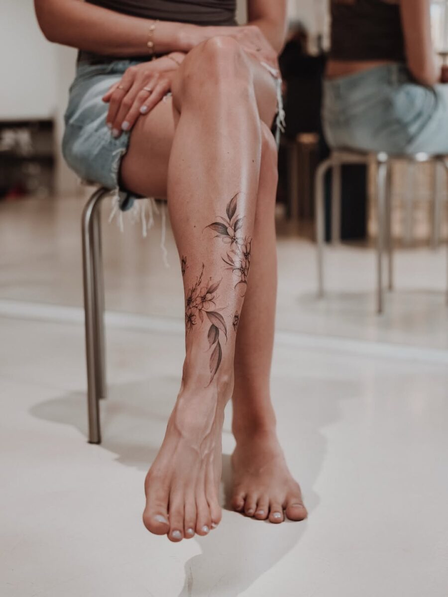 Delicate floral ankle tattoo with leaf accents