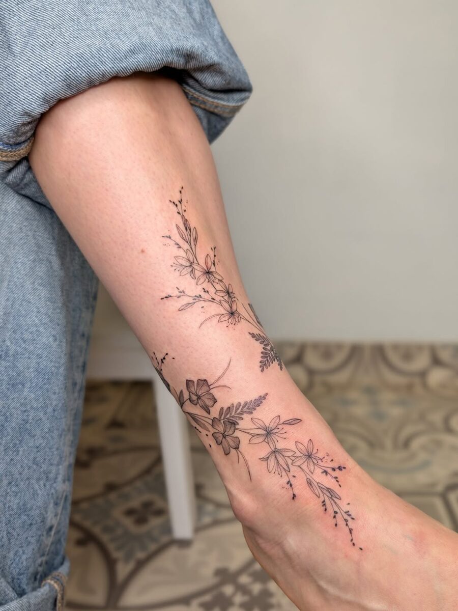 Elegant blackwork floral ankle tattoo design